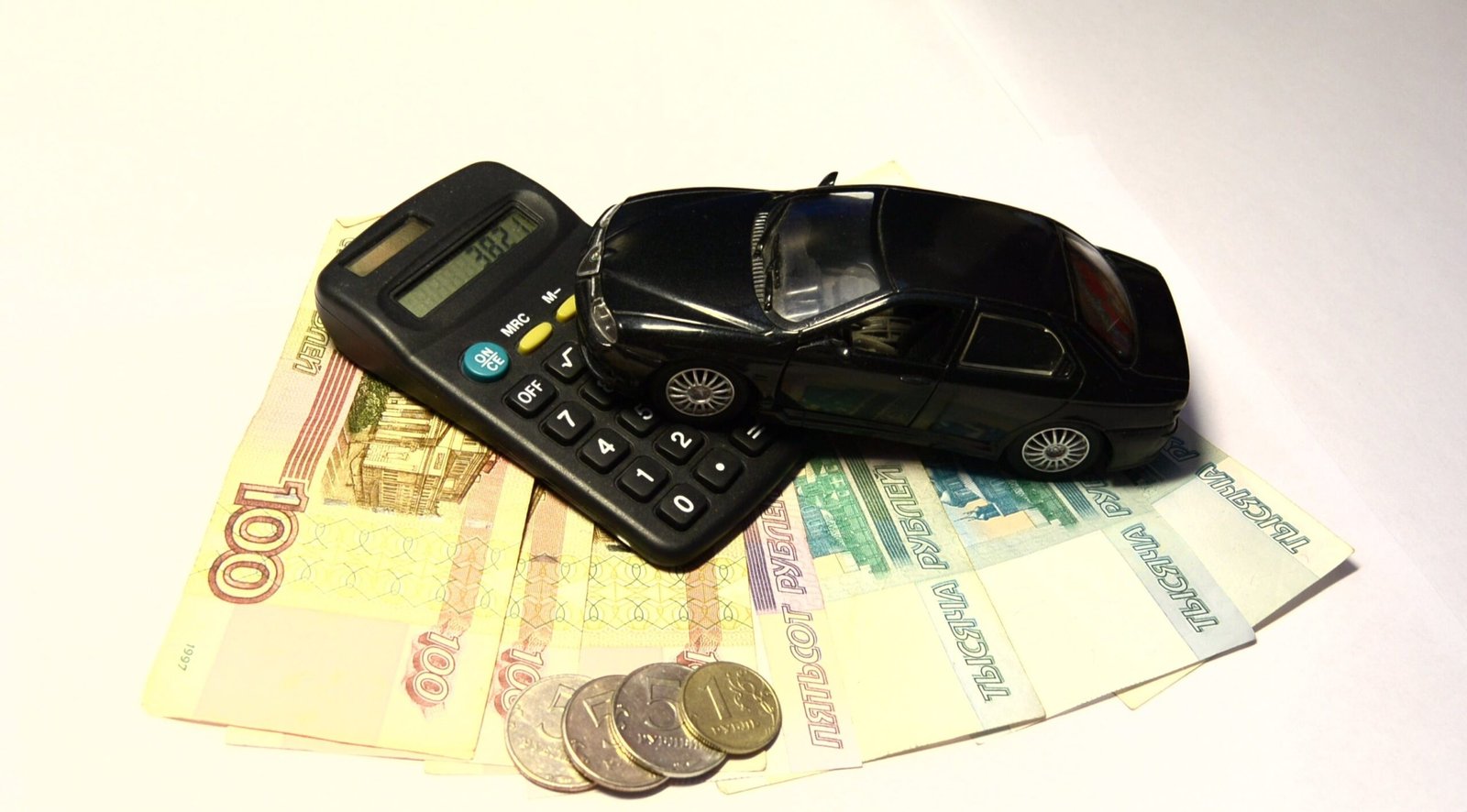 Toy car, calculator and cash representing the cost of buying and registering a vehicle