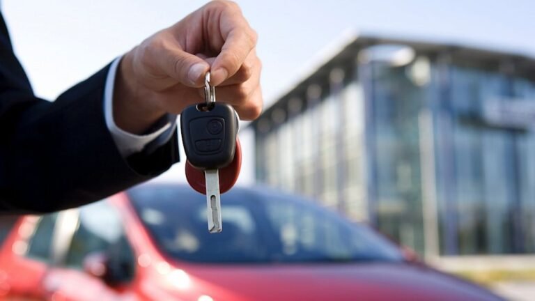 Car salesman handing over keys to a buyer in front of a dealership